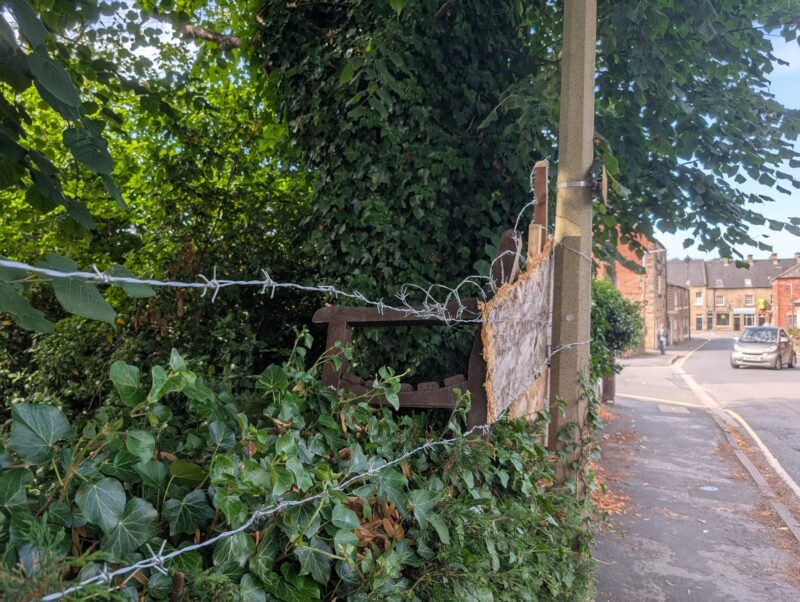A propped up bench with barbed wire to block entry onto the site.